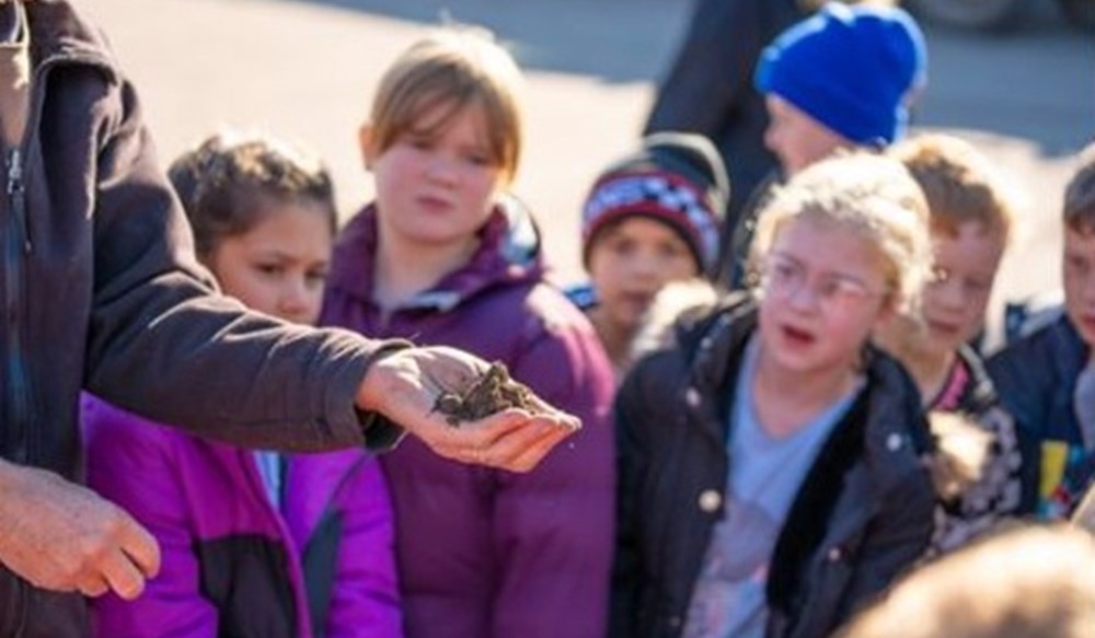 Children looking at a farmer holding soil.